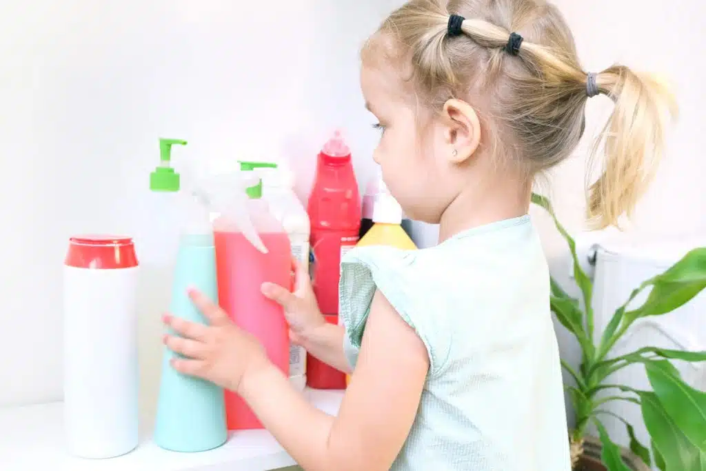 Une petite fille avec des produits ménagers dangereux