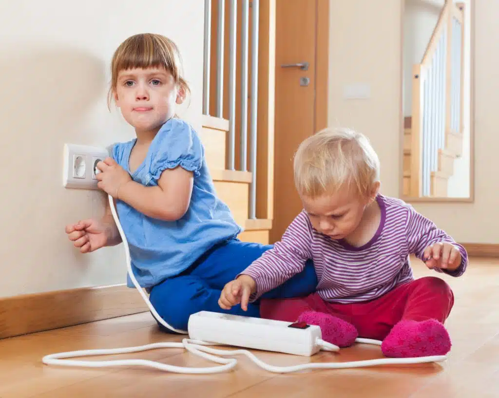 Deux enfants jouent avec une prise électrique et une multi prise