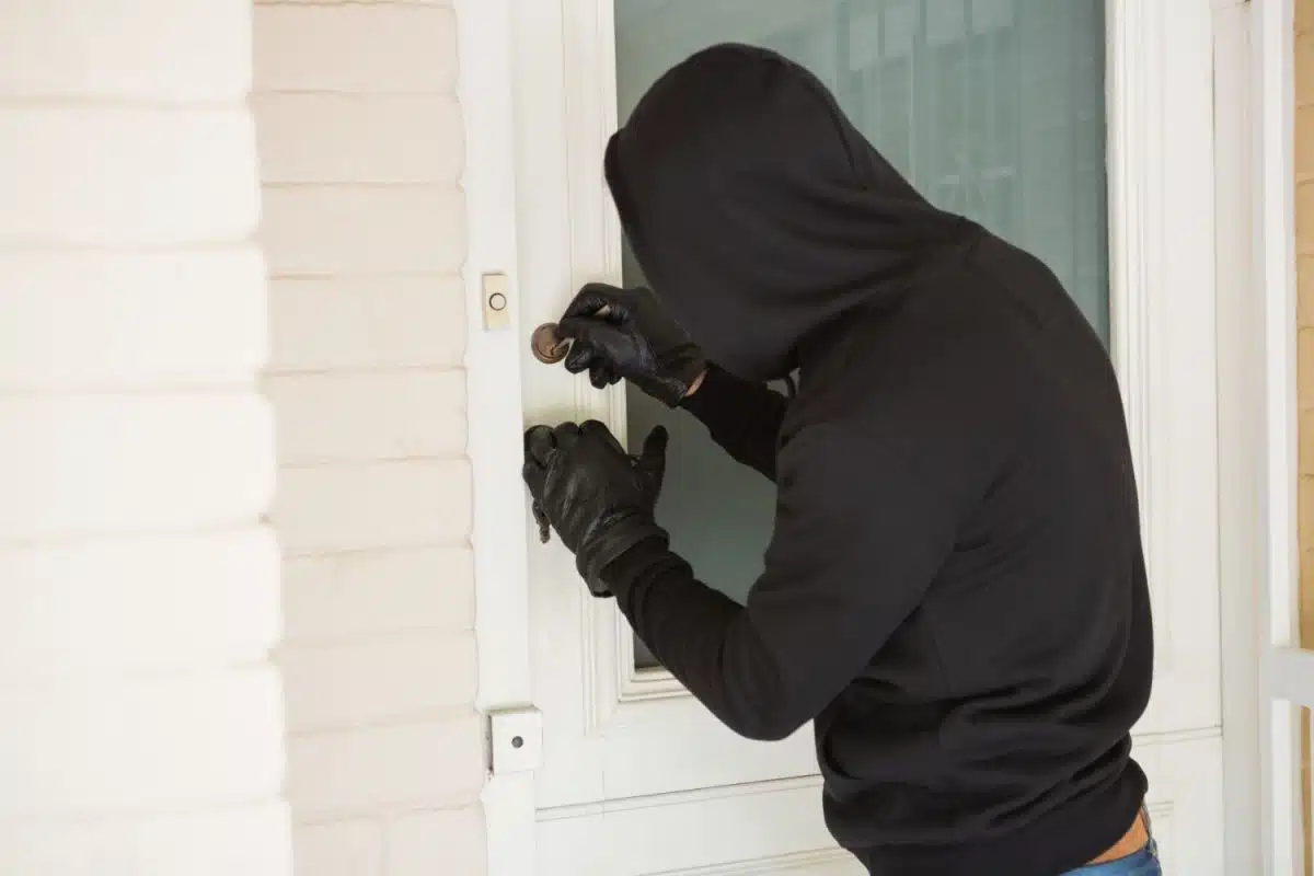 Un voleur entrain de forcer la porte d'une maison