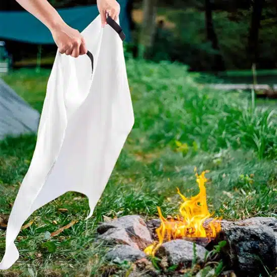 Une couverture anti feu va être posée sur un feu à l'extérieur